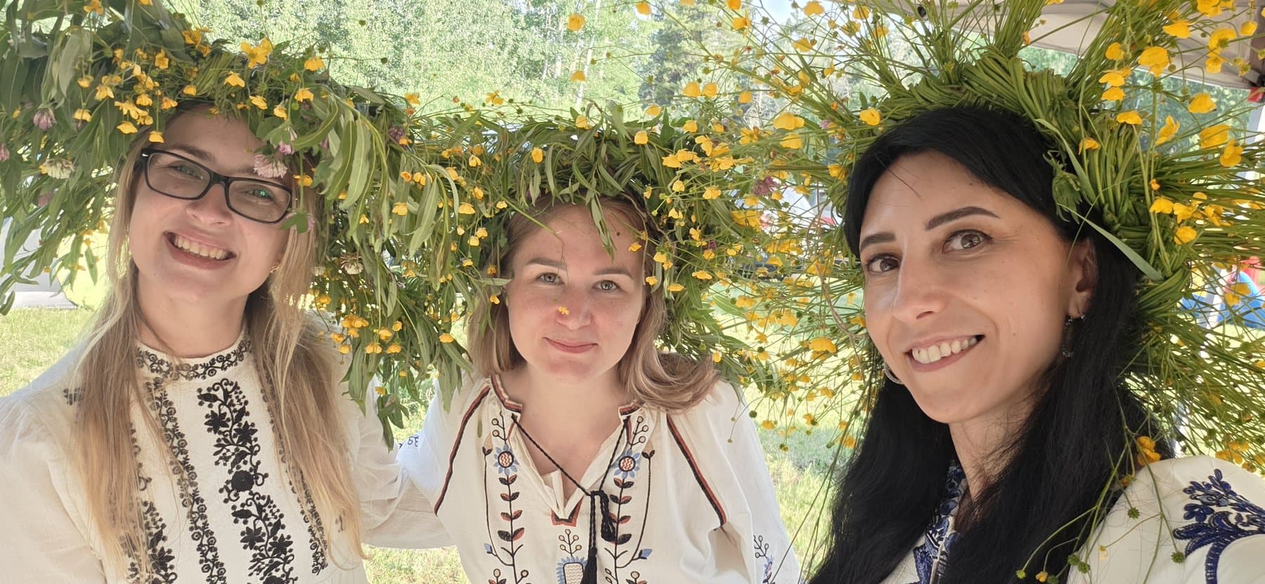 Olha Vozna and two women smiling beneath large flower crowns