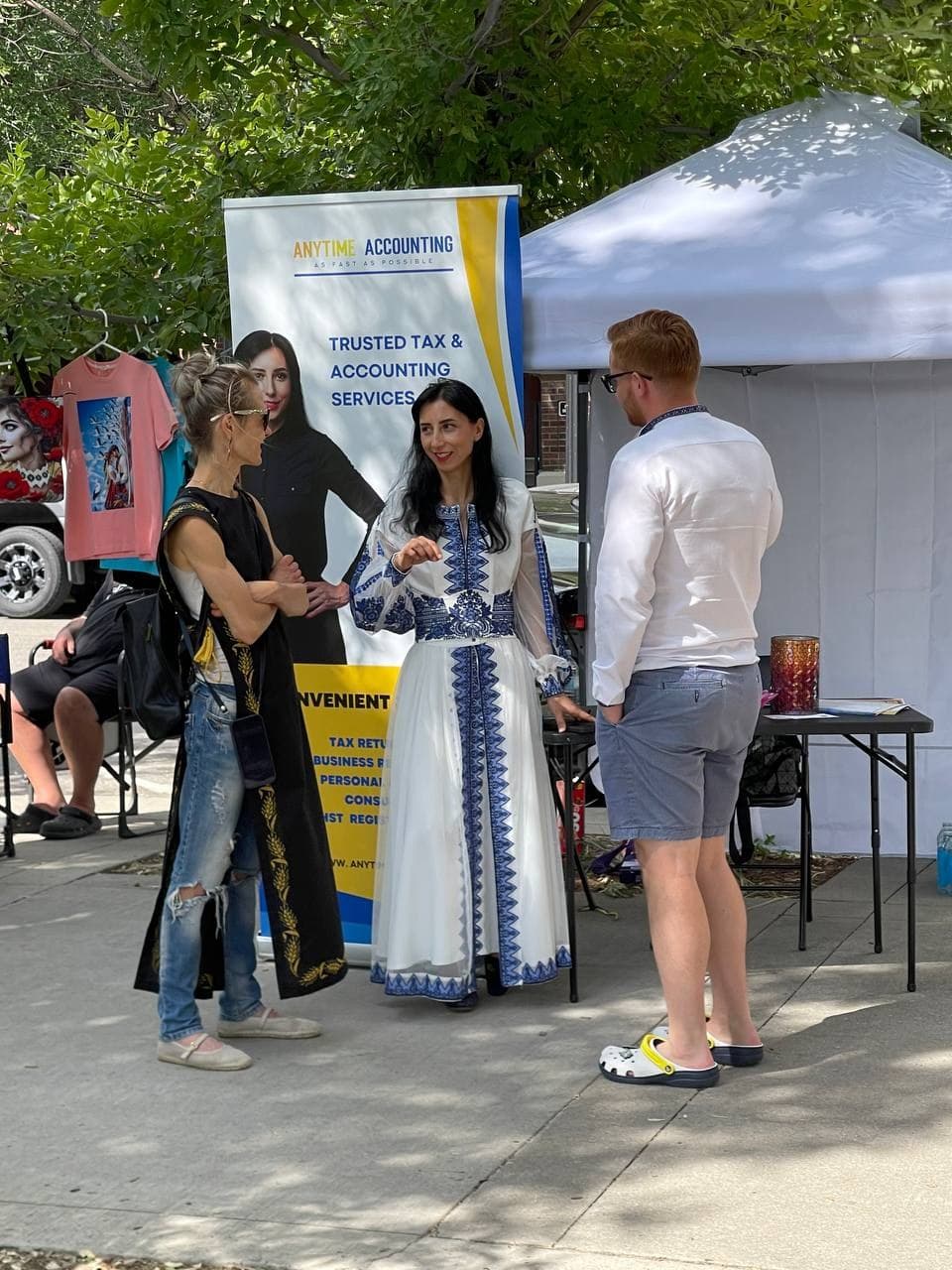 Ольга розмовляє з двома відвідувачами біля банера Anytime Accounting