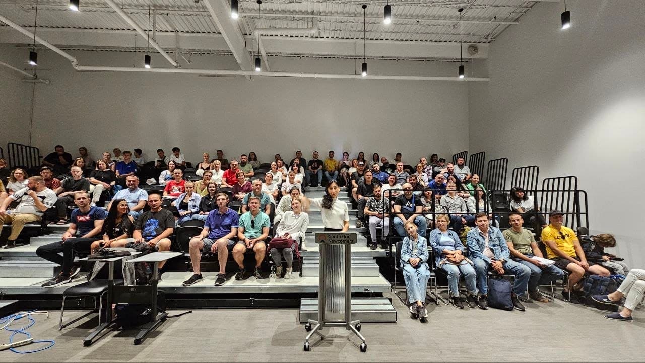 Olha Vozna at the Centre for Newcomers podium in front of a full auditorium