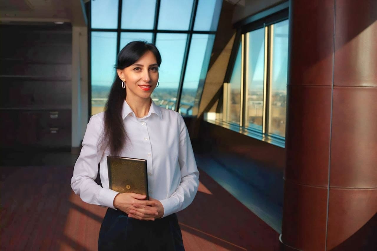 Olha Vozna holding a folder by the office windows