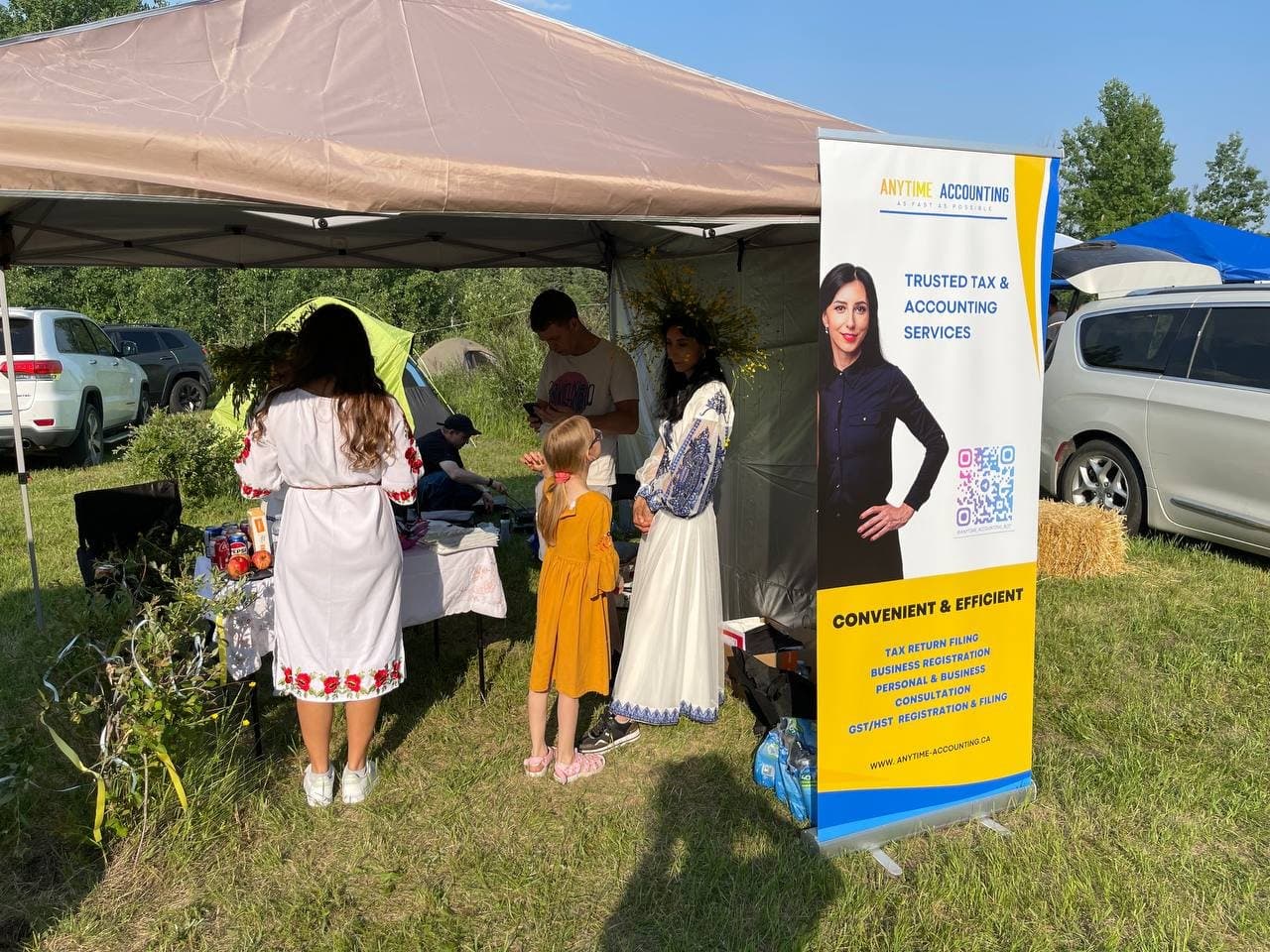 Festival visitors gathered at the Anytime Accounting booth beside the company banner