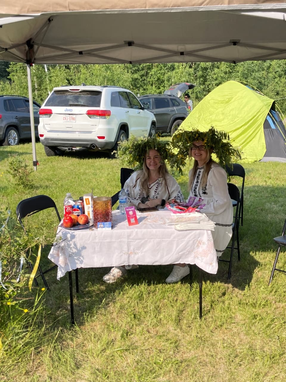 Two women wearing flower crowns at a table beside the Anytime Accounting tent