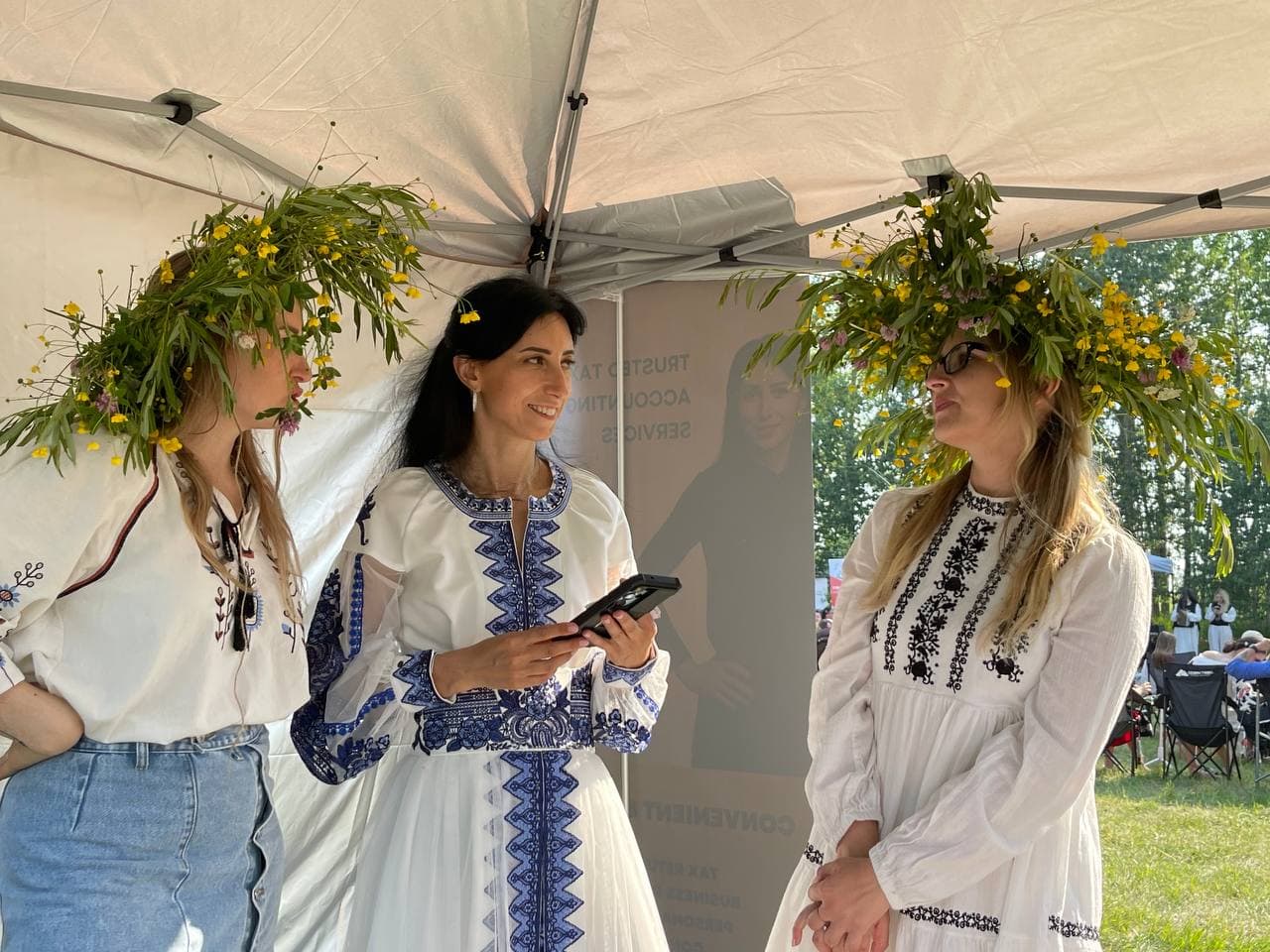 Olha Vozna talking with two festival guests in traditional Ukrainian clothing